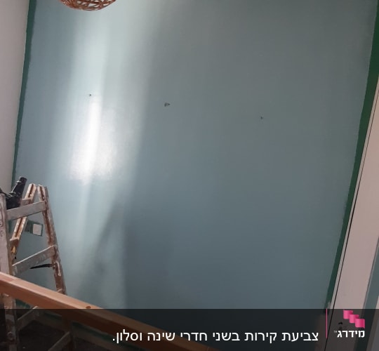 קיר צבוע בכחול עם סולם ועבודת צבע
